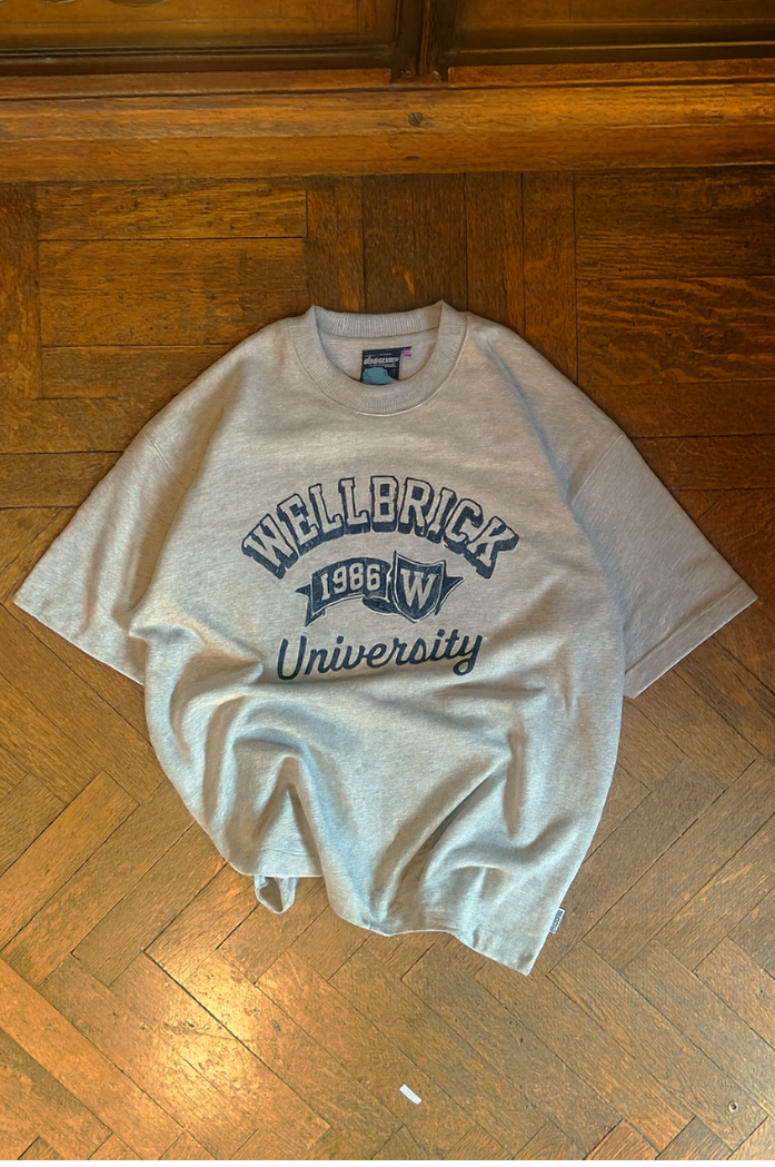 Gray t-shirt with 'Wellerick University' text on a wooden floor