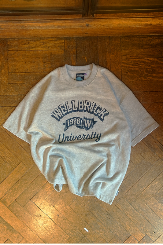 Gray t-shirt with 'Wellerick University' text on a wooden floor